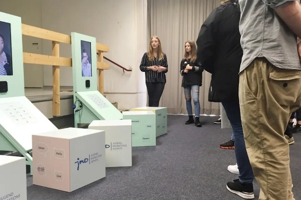 Mehrere junge Menschen sehen sich auf der Ausstellung Videointerviews an