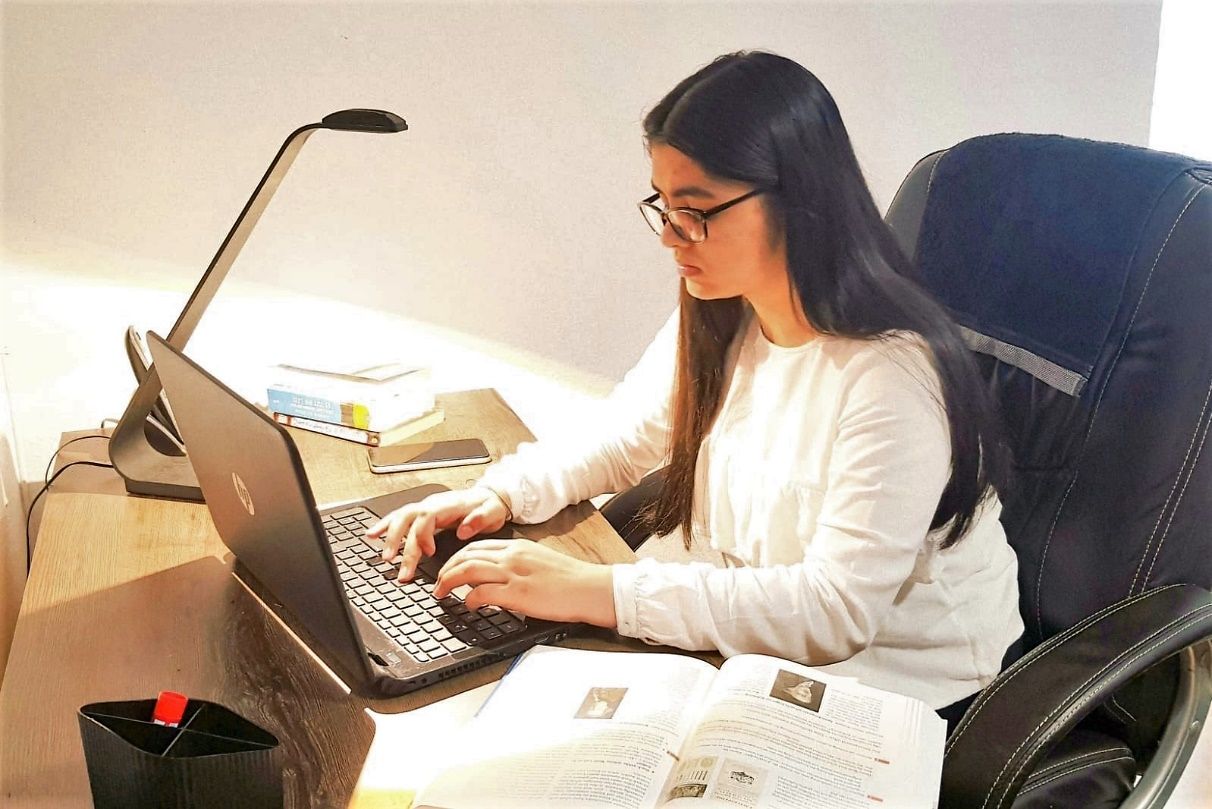 Schülerin sitzt an einem Schreibtisch vor einem Laptop