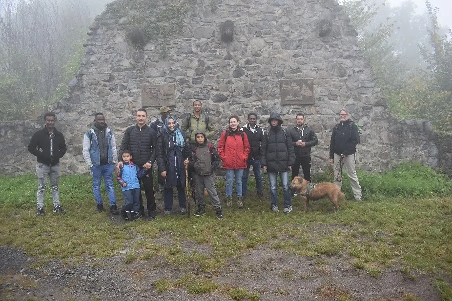 Eine Gruppe junger Menschen steht vor einem großen Stein