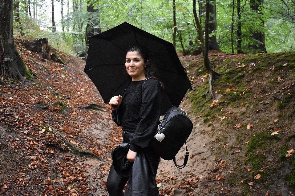 Eine junge Frau mit Schirm auf einem Wanderweg im Wald