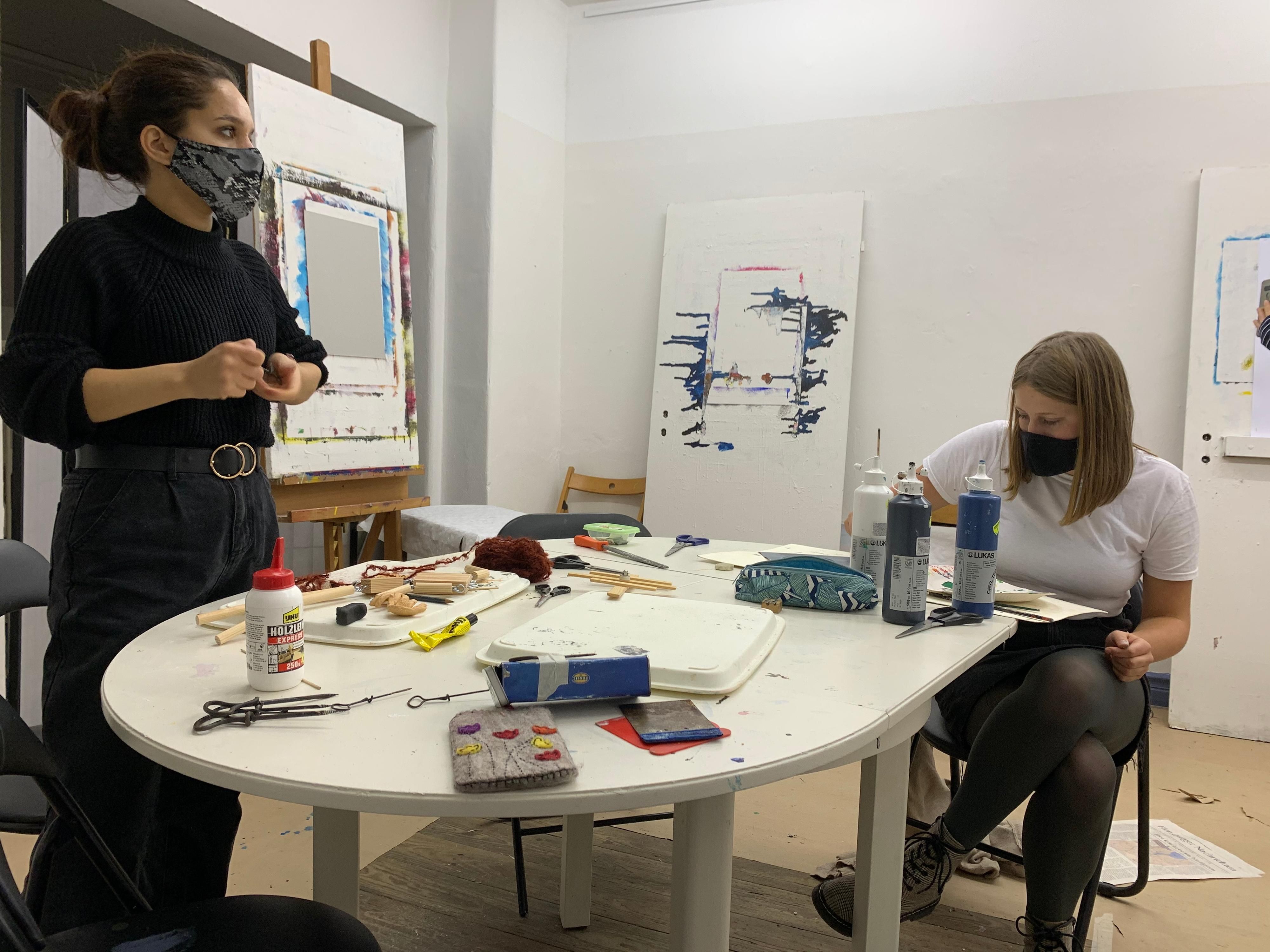 Zwei Frauen gestalten an einem Tisch ihre Kunstwerke.