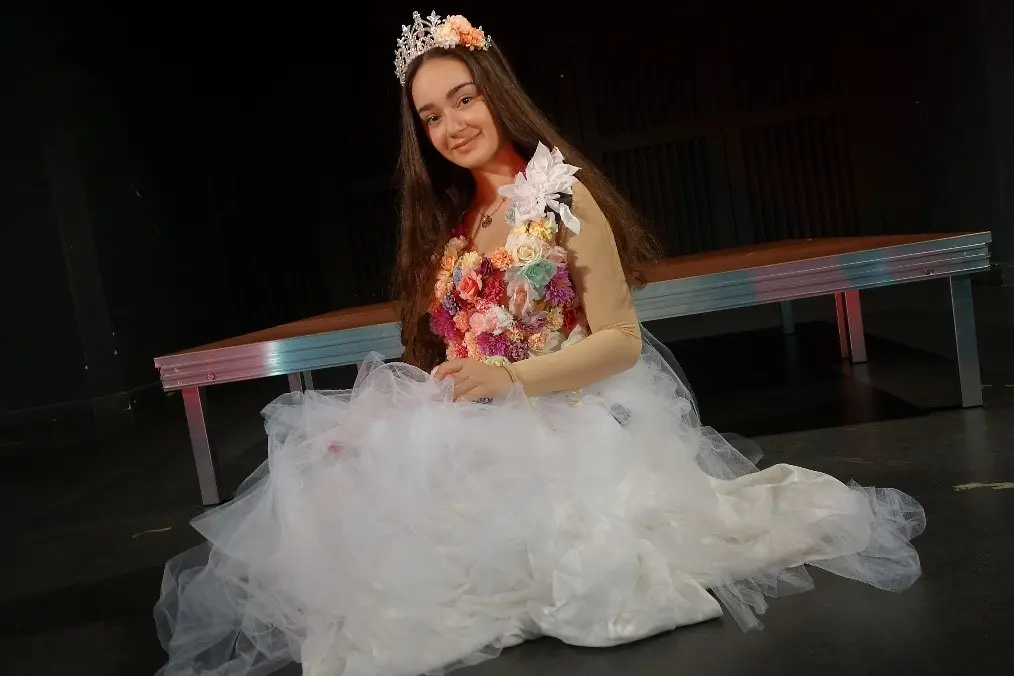 Ein junges Mädchen auf dem Bodenkiehend mit Kleid und Krone auf dem Kopf