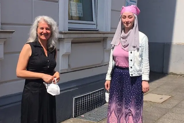 zwei Frauen,Ayça Okçu-Seçer und Ginan Al Hussein, stehen vor einem Haus