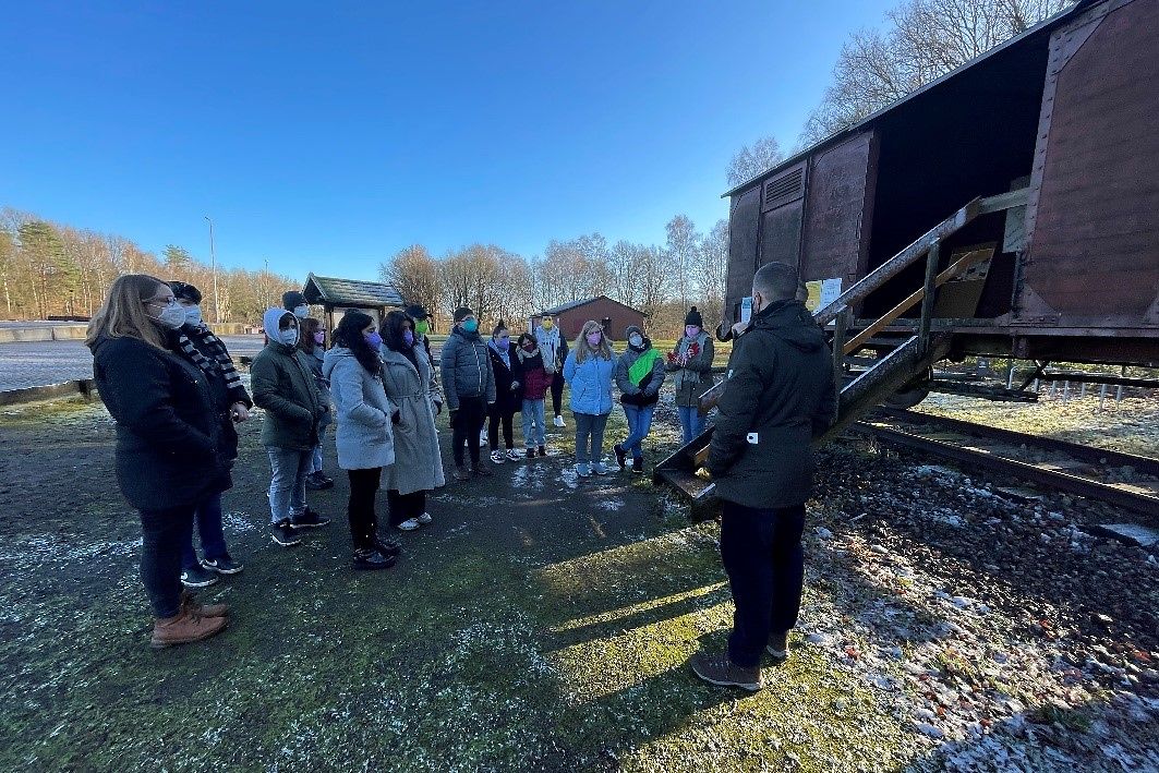 Ein große Gruppe junger Menschen steht vor einen Wagon