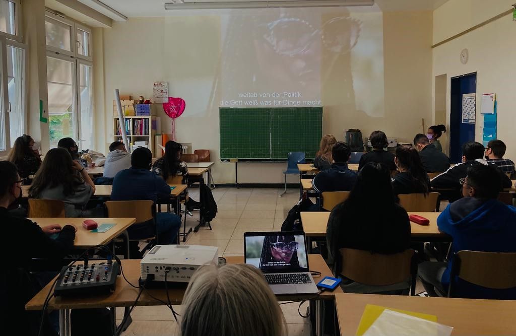 Schüler sitzen in einem Klassenraum und gucken einen Film.