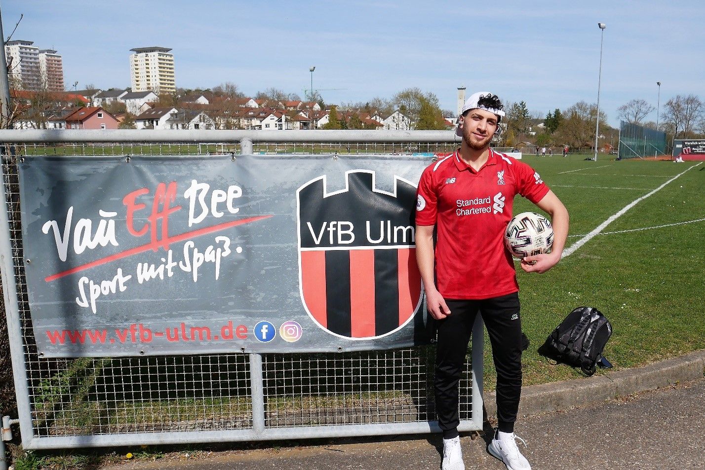 Ein junger Mann steht vor einem Fußballfeld