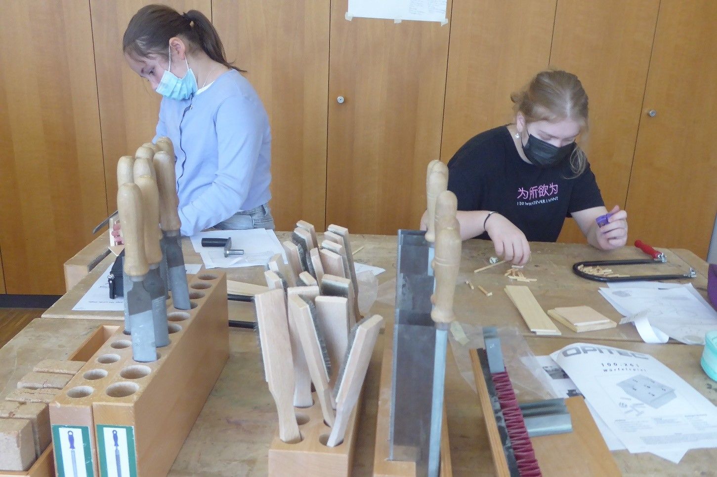 Zwei Mädchen stehen an einer Werkbank und machen Holzarbeiten