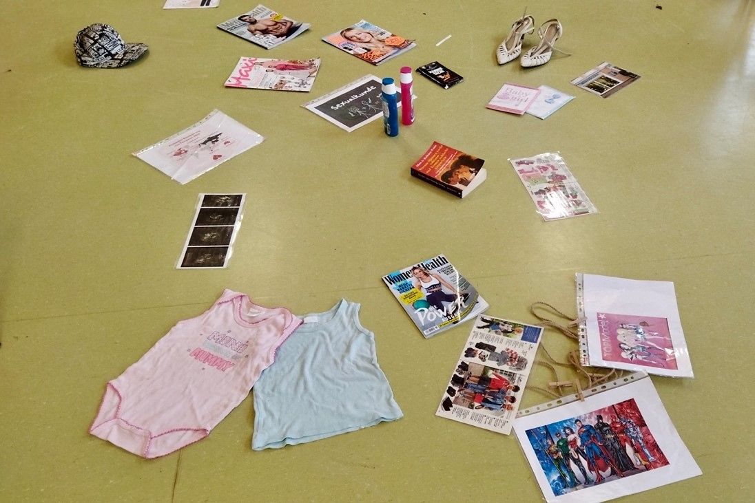 Kinderkleidung, Zeitungen und Fotos liegen auf dem Boden