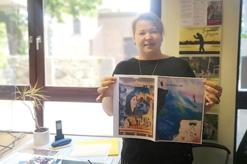 Frau Oksana Blattner hält Bilder mit aktuellen Motiven von Rayid Barkisch in die Kamera.