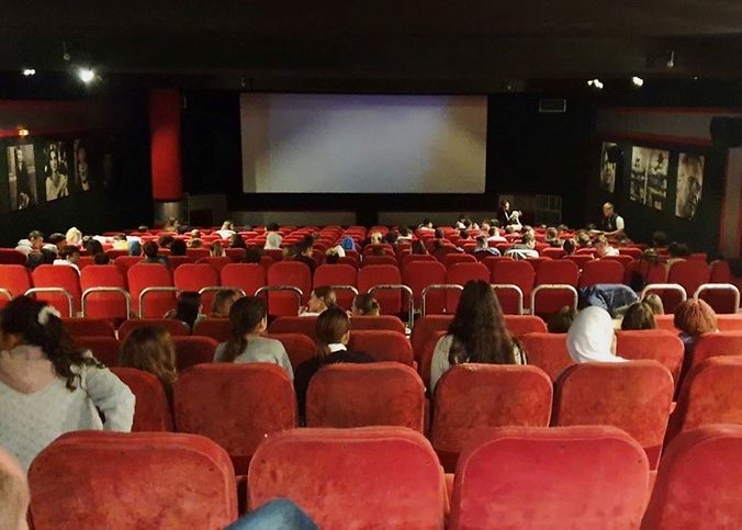 Ein Kinosaal mit einigen Zuschauern die auf die Leinwand gucken