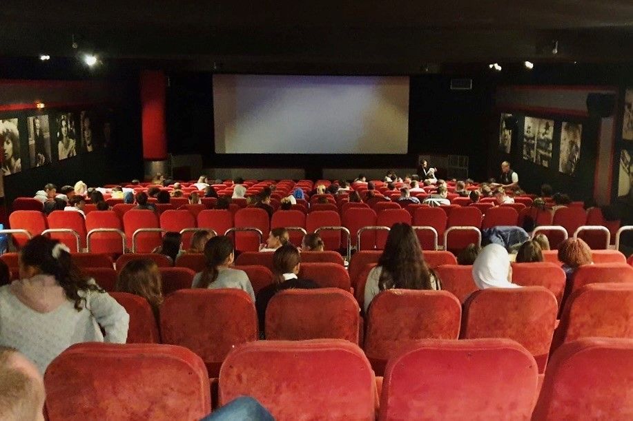 Ein Kinosaal mit einigen Zuschauern die auf die Leinwand gucken