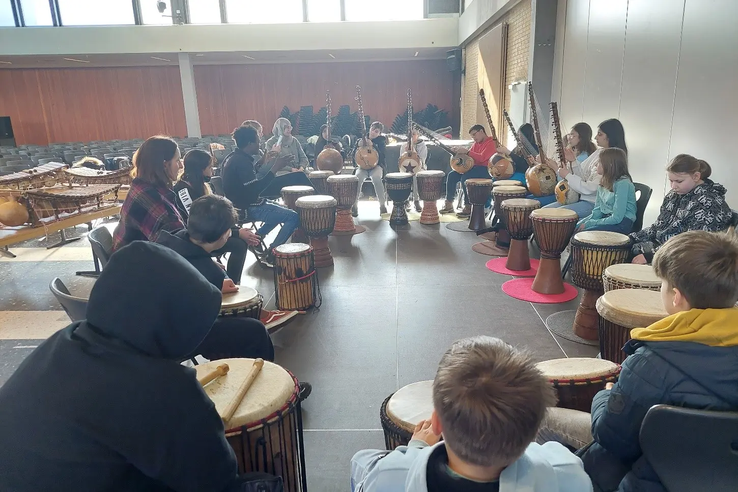 Eine Gruppe von Schülern sitzt im Kreis mit Trommeln
