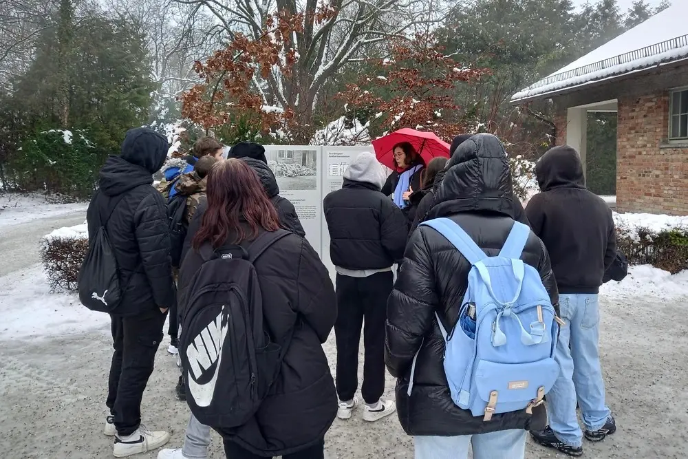 Eine Gruppe steht vor einem Gebäude und einer Gedenktafel.