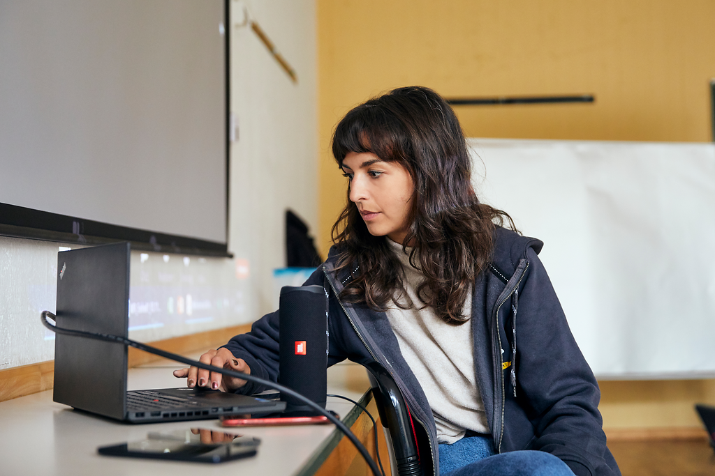 Eine junge Frau sitzt vor einem Laptop.