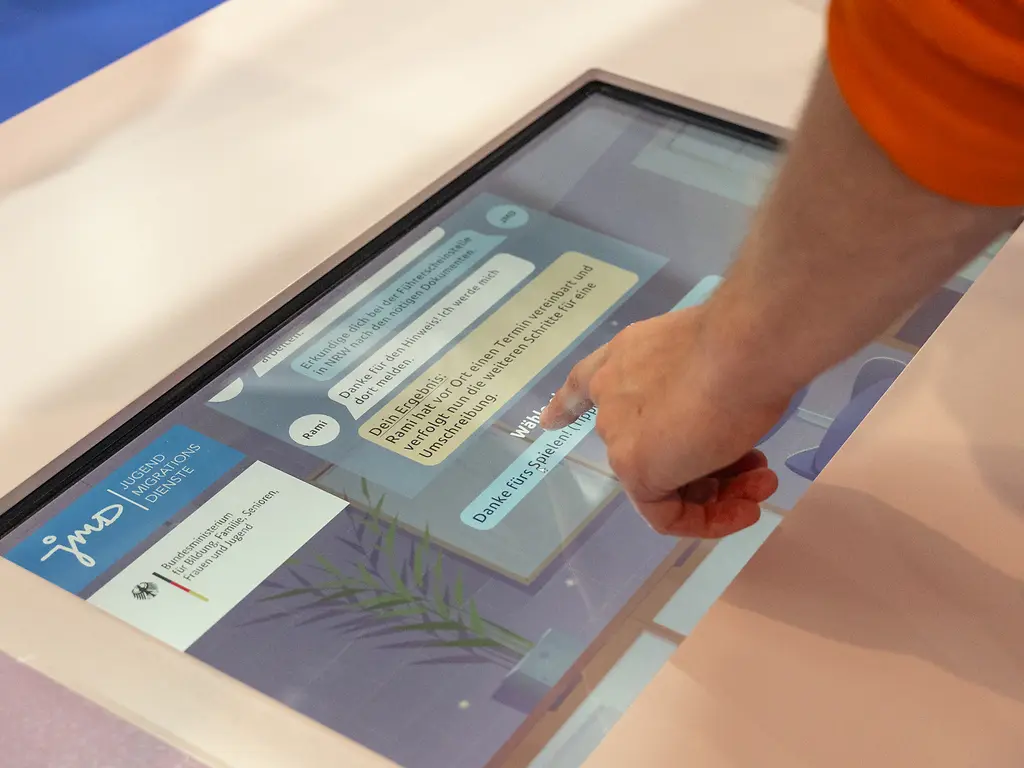 Ein Touchscreen-Monitor auf dem man im virtuellen Rollenspiel mehr über die JMD-Beratung erfahren kann.