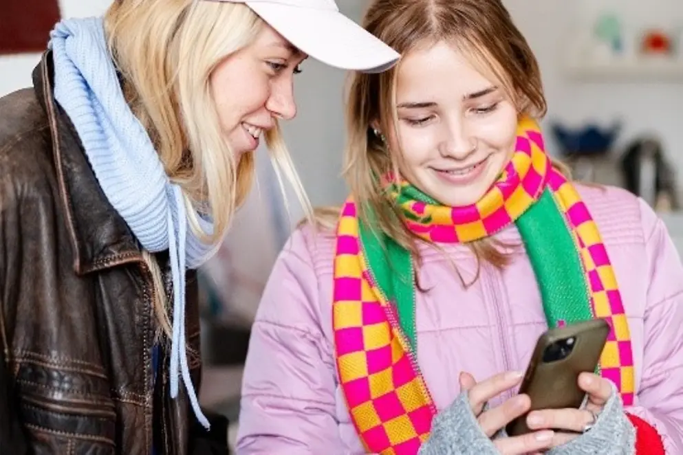 Zwei junge Mädchen gucken auf ein Handy.