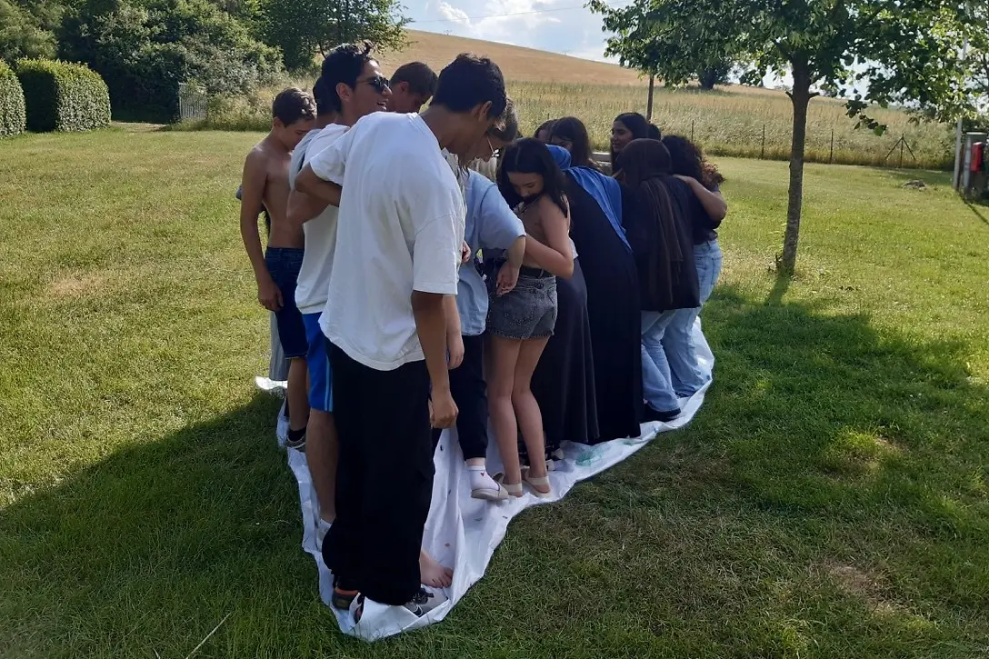 Eine große Gruppe von Schülern steht auf einer Wiese auf einem großen Tuch.