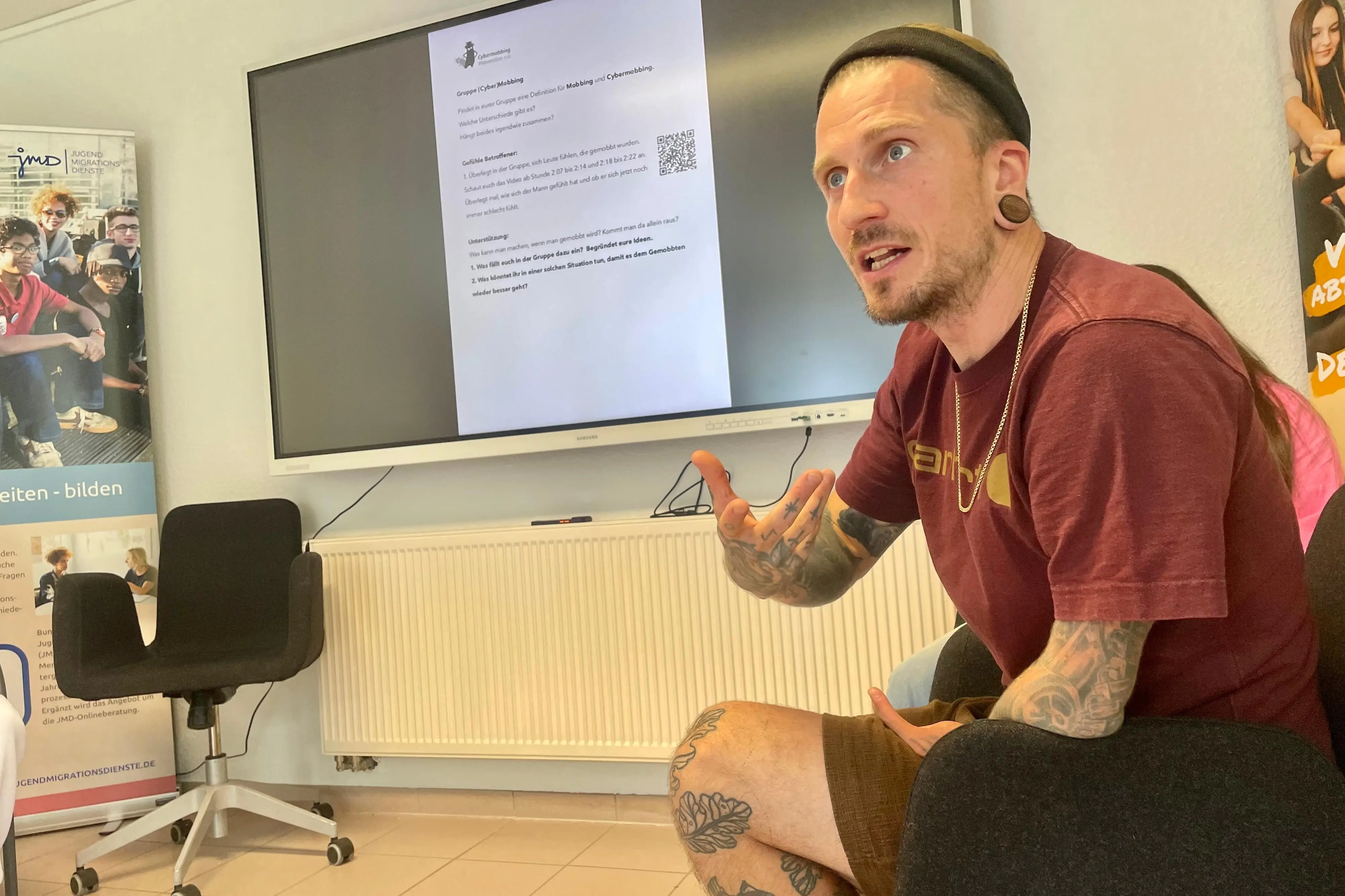 Ein Mann sitzt auf einem Stuhl vor einer Leinwand