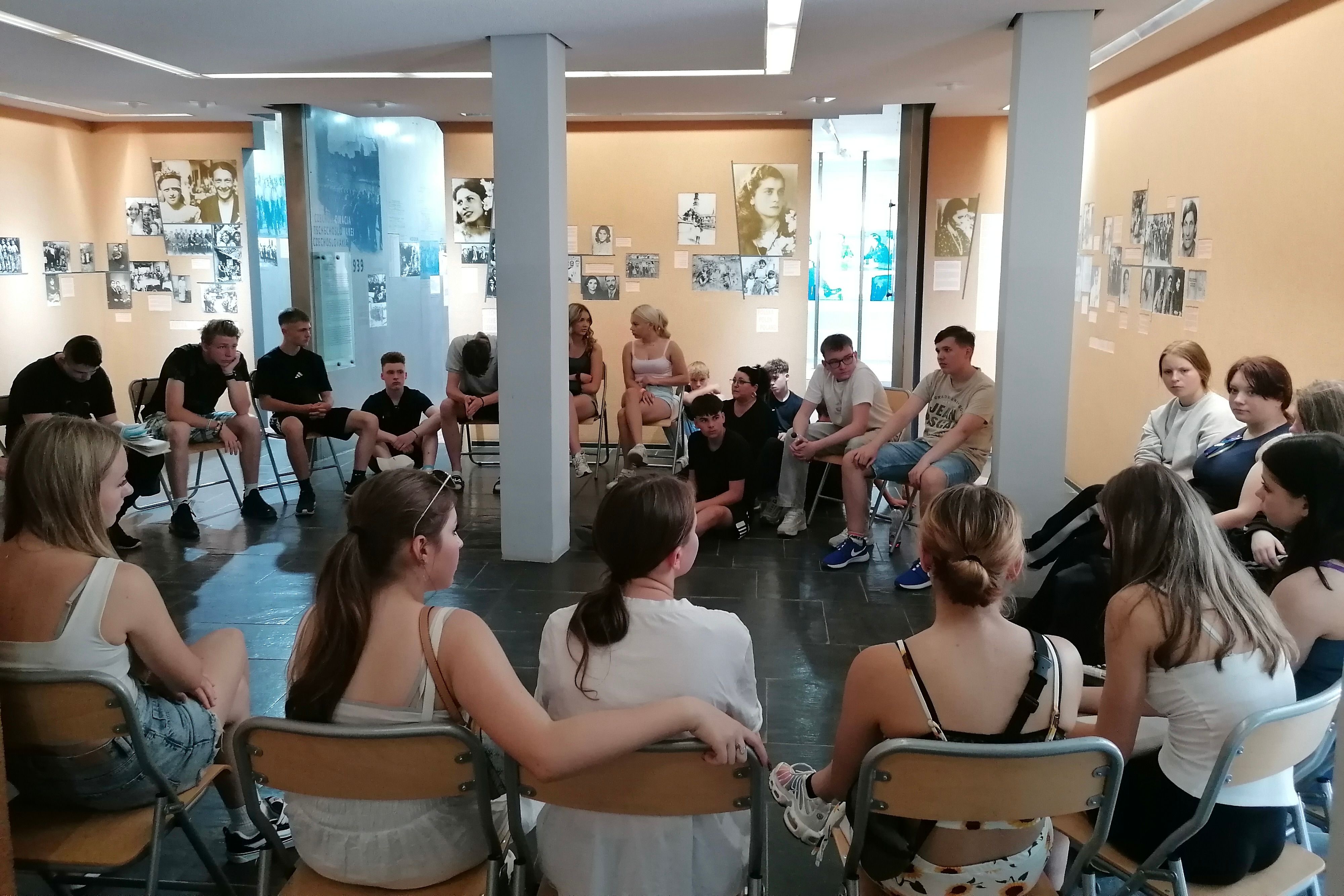 Eine Gruppe von Jugendlichen sitzt in einem Raum im Kreis.