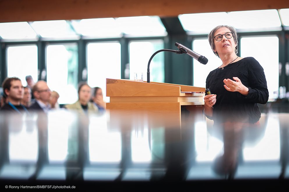 Eine Frau steht an einem Rednerpult und hält einen Vortrag.