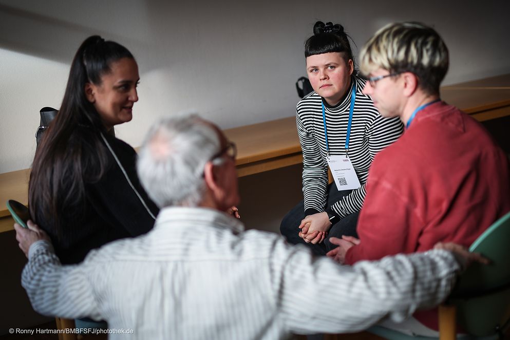 Eine Gruppe von vier Personen sitzt im Kreis.