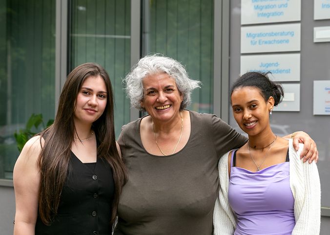 Drei Frauen stehen vor einem Haus.