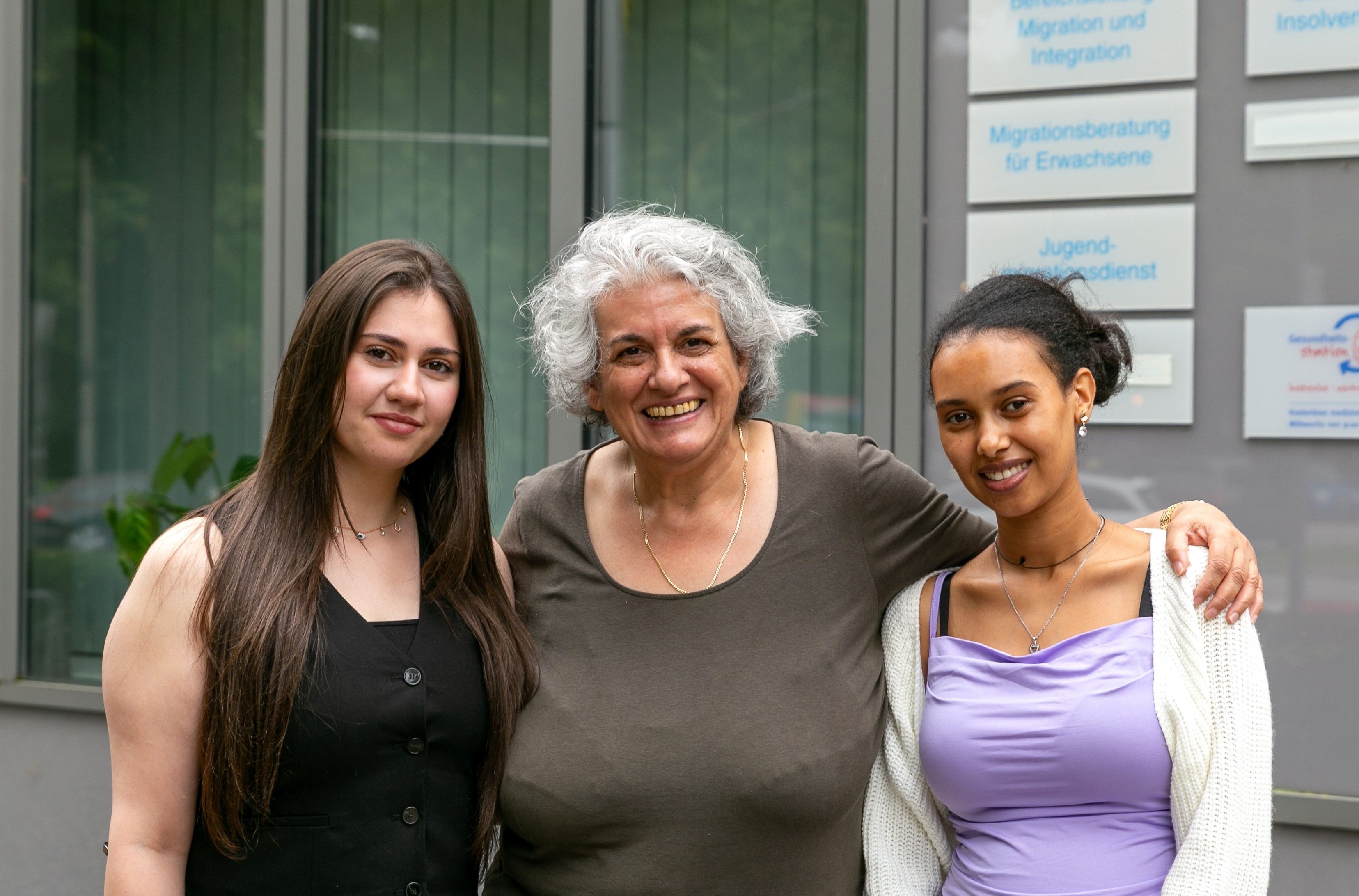 Drei Frauen stehen vor einem Haus.