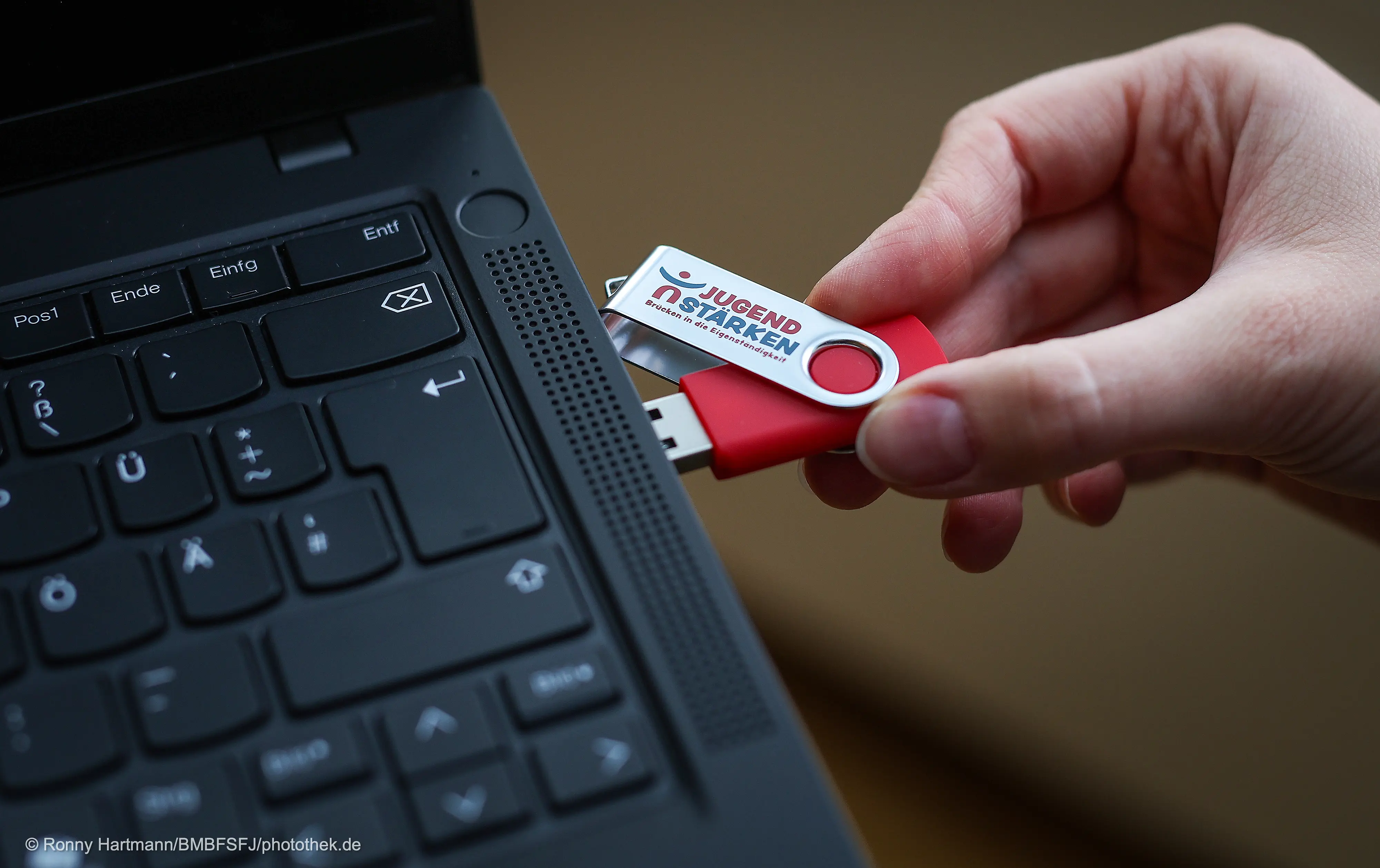 Eine Ecke von einem Laptop, in den ein USB-Stick gesteckt wird.