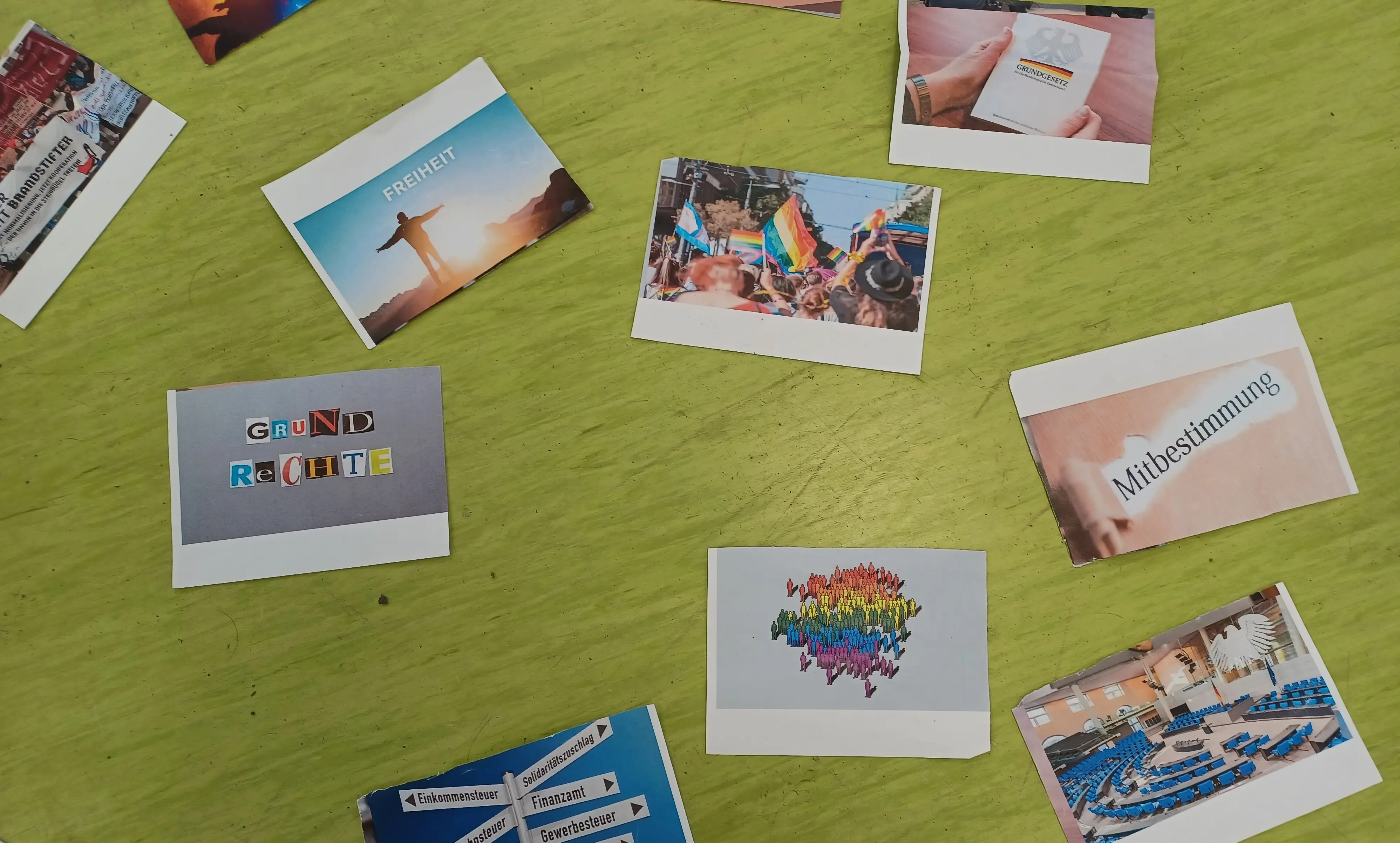 Das Foto zeigt verschiedene Fotos, die auf einem Tisch liegen und Aspekte der Demokratie darstellen sollen.
